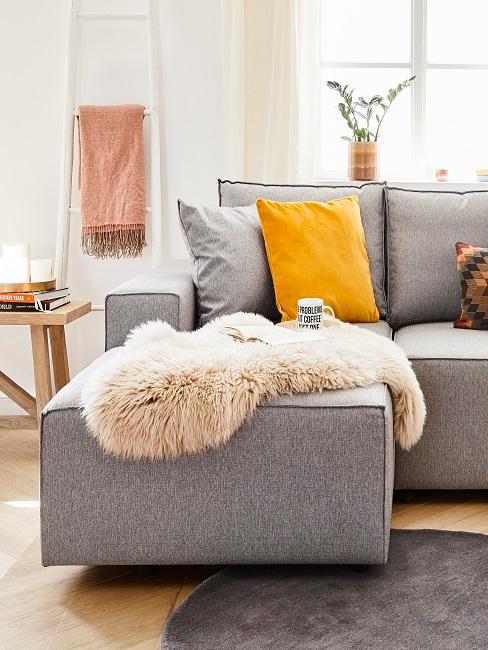Graues Sofa im Wohnbereich mit einem gelben Kissen