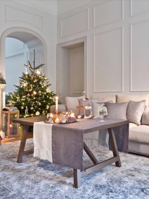 Feestelijk gedekte tafel voor de zitbank met daarachter een kerstboom
