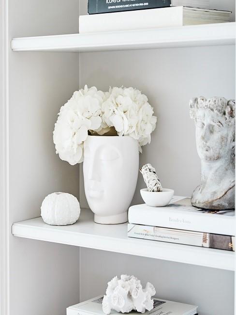 Vase mit Gesicht Weiße Vase mit Gesicht und weißen Blumen in Regal
