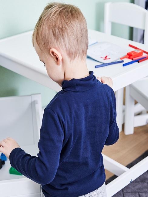 Junge steht vor Schreibtisch