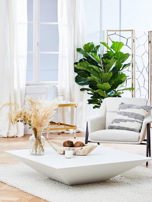 tendances deco 2020 salon couleurs claires, table basse blanche, elements deco accents dores, laitonnes, fauteuil large blanc, rideaux blancs, plantes grandes feuilles vertes