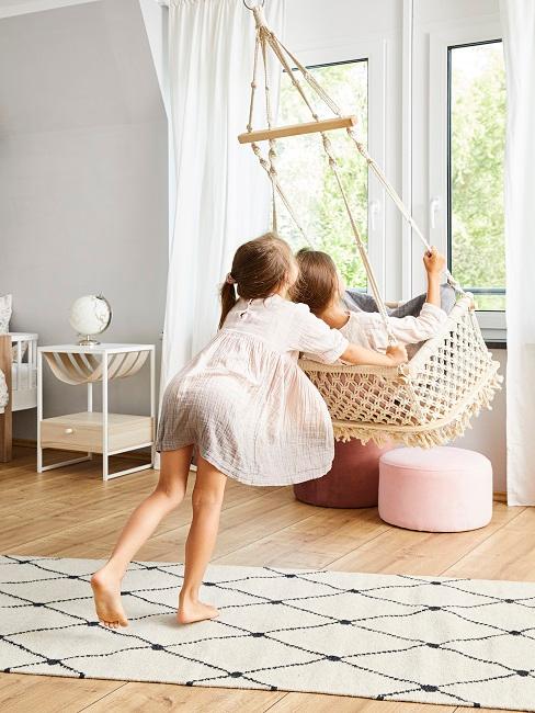 Familienzeit Wohnzimmer mit Hängesessel, ein Kind schaukelt das andere