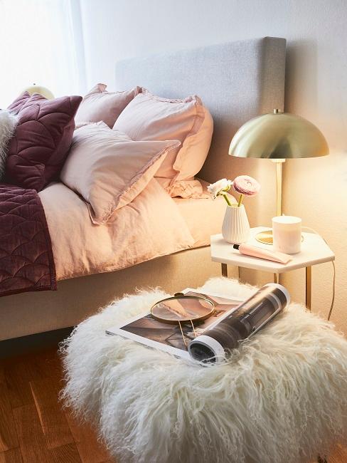 Schlafzimmer im maximalistischen Stil mit goldener Tischleuchte und einem Pouf aus Kunstfell in Weiß
