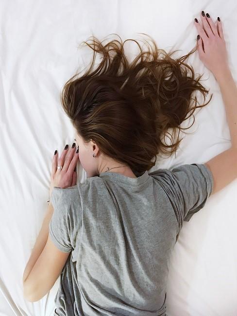 Schlafposition Bauchschläfer: Frau liegt auf dem Bauch im Bett