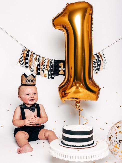 Geschenke zum 1. Geburtstag Baby neben Kuchen Geschenke zum 1. Geburtstag Baby neben Kuchen und Luftballon