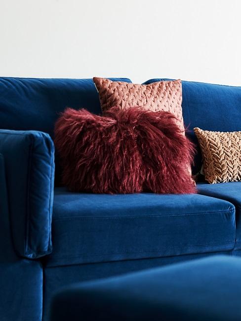 Blaue samt Couch mit roten Kissen
