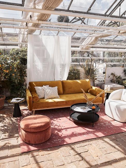 Wintergarten mit gelber Couch neben roten Dekoelementen