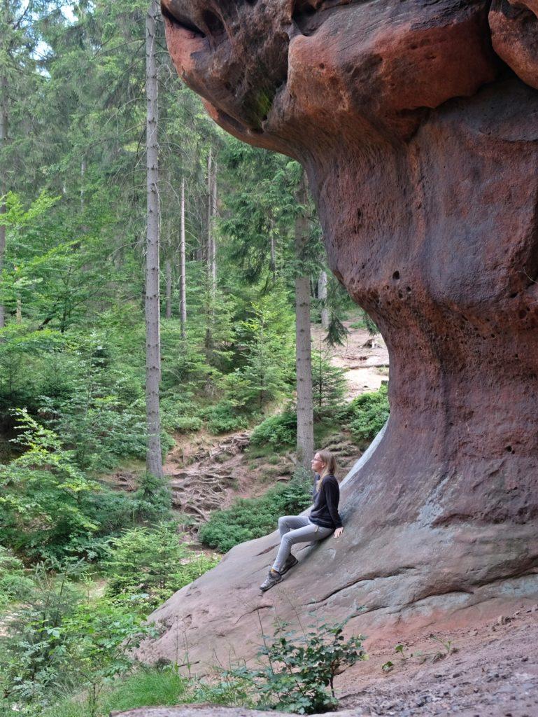 Frau an einem Berg im Wald sitzend