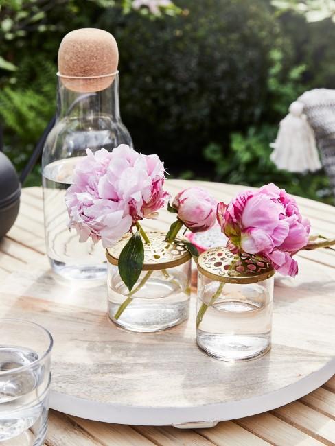 Pfingstrosen in kleinen Vasen auf dem Tisch im Garten