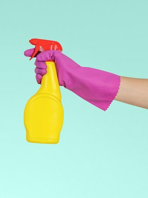 una mano en un guante rosa con un detergente amarillo