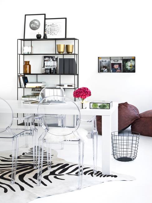 vivir-en-un-estudio Estudio blanco decorado con estantería y mesa auxiliar negra y mesa y sillas transparentes