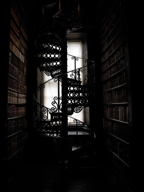 Biblioteca con ventanal al fondo y escalera de caracol metálica en el medio