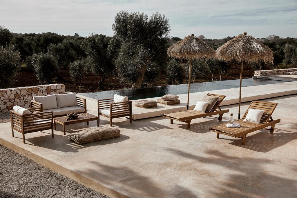 Terraza con piscina infinity y chaises-longues bajo sombrillas de palmera