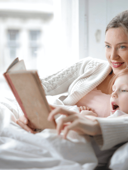 madre leyendo a su hija en cama