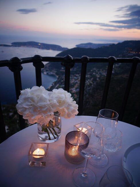 mesa blanca con flores en terraza al atardecer