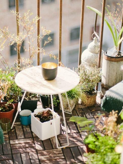 Balcon pequeño con mesa blanca y plantas
