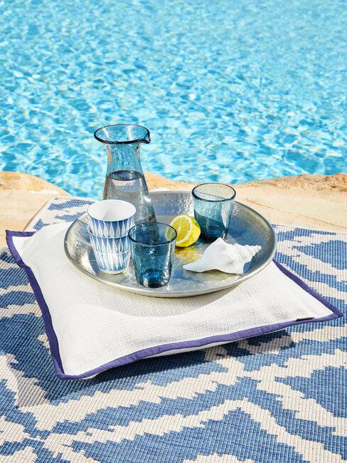 piscina, cojin y bandeja con vasos azules