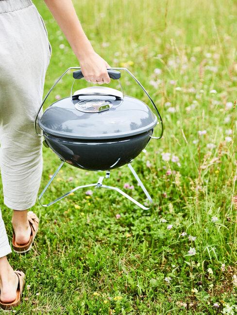 persona cargando barbacoa exterior en cesped