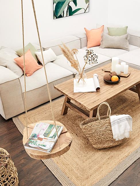 Salon avec canapé beige, table basse en bois, balancoire en bois, tapis en jute et panier en osier