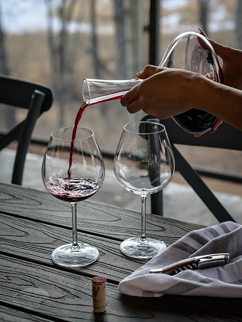 une personne entrain de servir un verre de vin avec une carafe