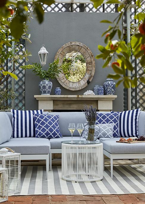 salon de jardin bleu avec table d'appoint ronde avec verre de vin, mur avec miroir et cheminée