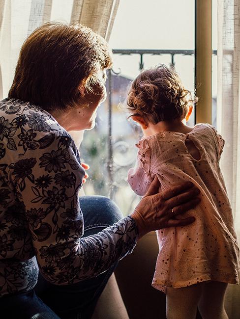 une mamie avec sa petite fille regardant par la fenêtre