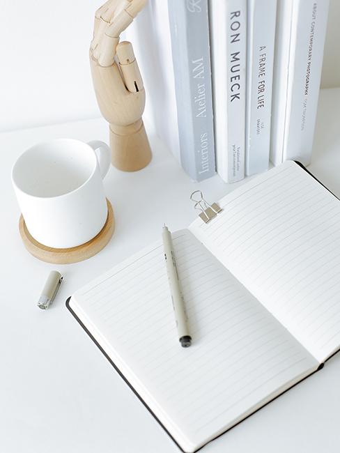 Carnet de notes sur une table blanche avec un style et une tasse