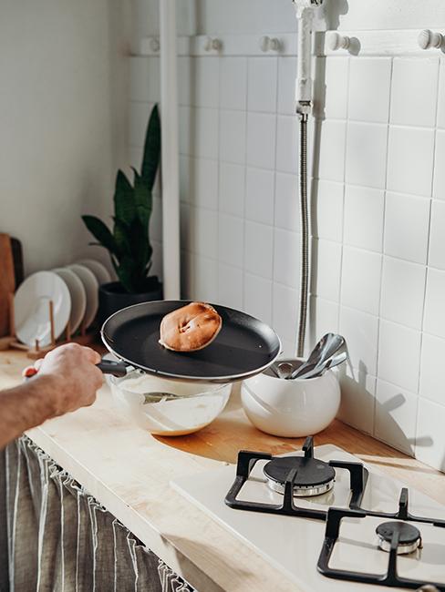 Une personne entrain de cuire un pancake dans une poel