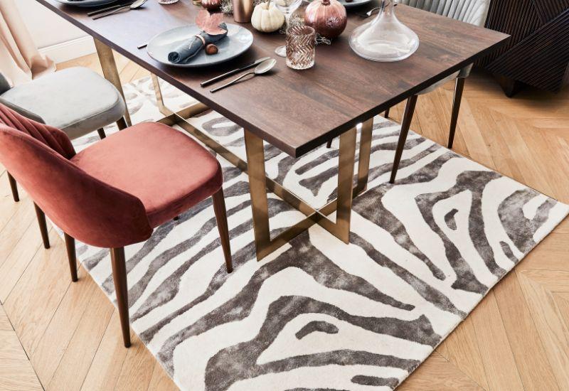 salle à manger avec table en bois moderne et tapis zèbre