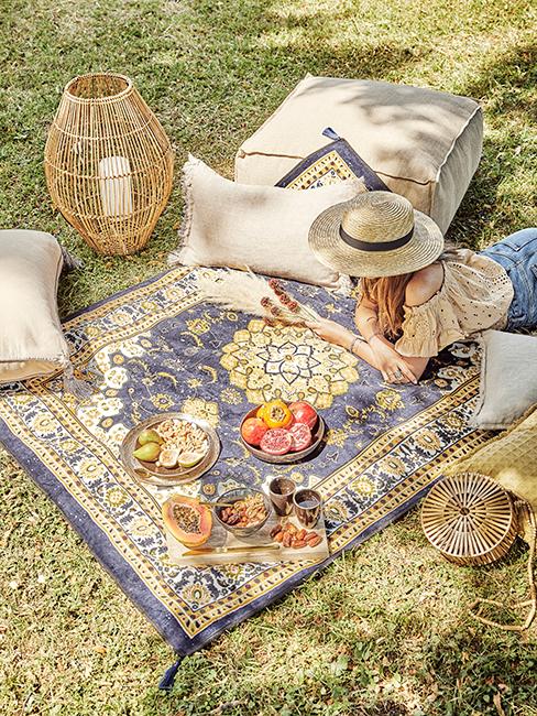 pique-nique dans l'herbe avec fille sur un tapis vintage entrain de lire, lanterne en bambou et coussins de sol