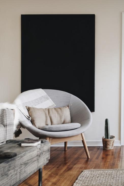 Fauteuil rond en textile gris avec pieds en bois et tableau noir