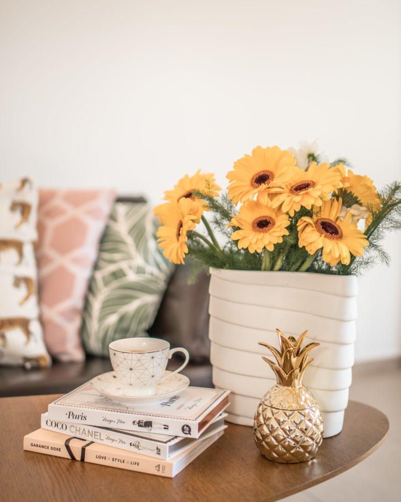 Séjour cocooning avec coussins, bouquet de fleurs jaunes et accessoires
