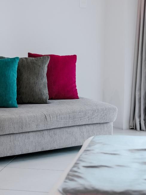 Méridienne grise avec trois coussins décoratifs en velours de couleurs différentes