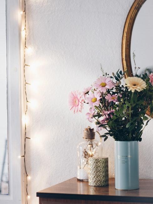 Miroir et bouquet de fleurs posé devant, une guirlande lumineuse décorant le mur