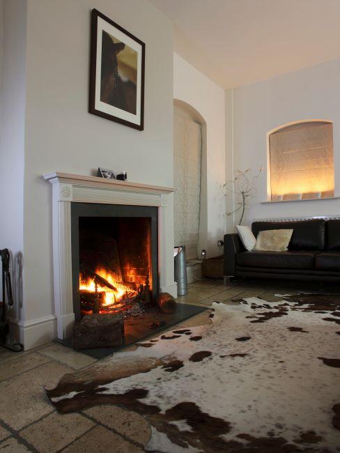 Intérieur avec cheminée blanche et tapis peau de vache