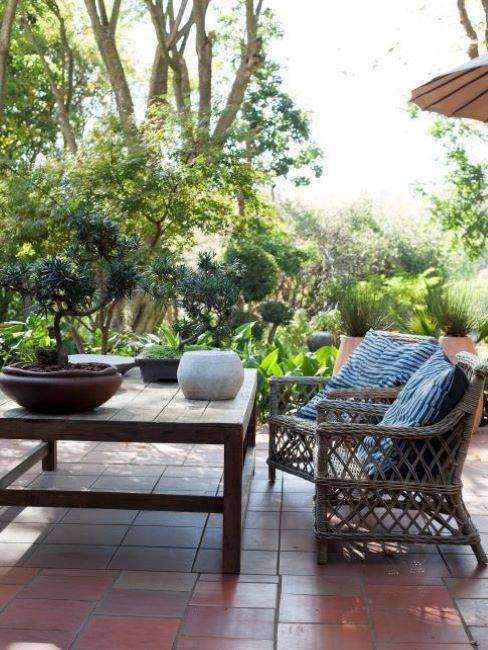 Terrasse avec salon de jardin en bois et avec carrelage en pierres rouge