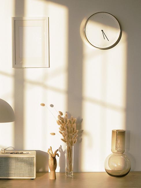 Horloge murale blanche accroché sur un mur blanc, avec déco boho et herebe de pampa