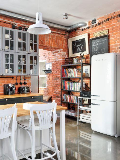 Cuisine avec mur de brique apparente, frigo et blanc, table et chaises en bois