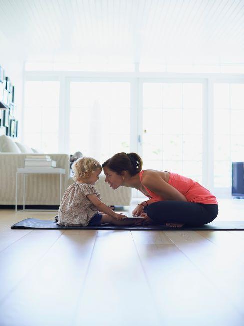 Femme avec son enfant sur un tapis de yoga dans le salon