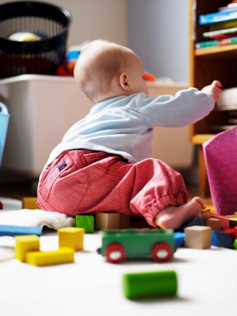 Enfant avec pantalon corail jouant avec des jouets en bois