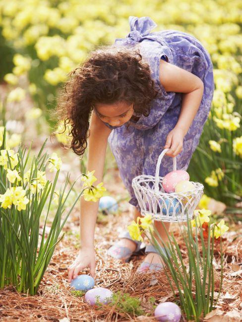 Petite fille cherchant des œufs de Pâques dans le jardin