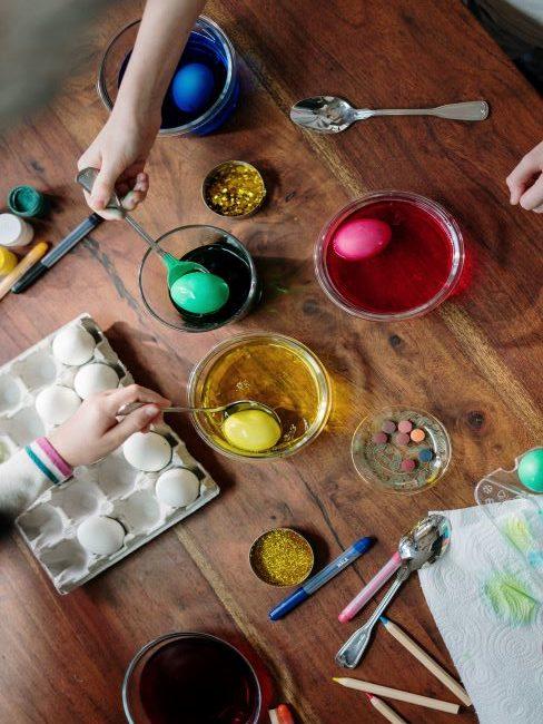 Personnes coloriant des œufs dans des bols avec différentes couleurs de peinture