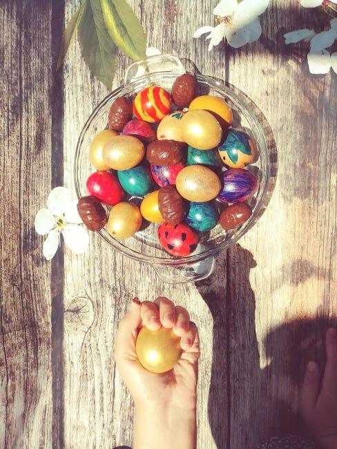 Bol avec œufs de Pâques en chocolat et main d'enfant tenant un œuf