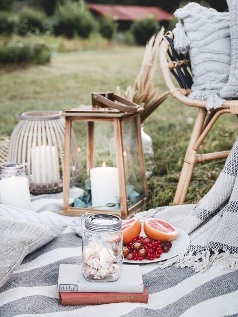 Pique-nique sur l'herbe avec une lanterne de jardin en bois avec bougies sur plaid
