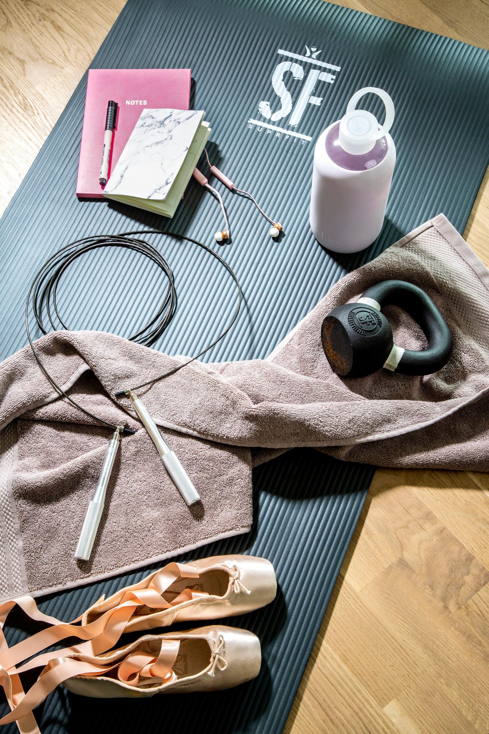 tapis d'exercices avec une corde a sauter, une paire de ballerines, un poids, des écouteurs et une gourde