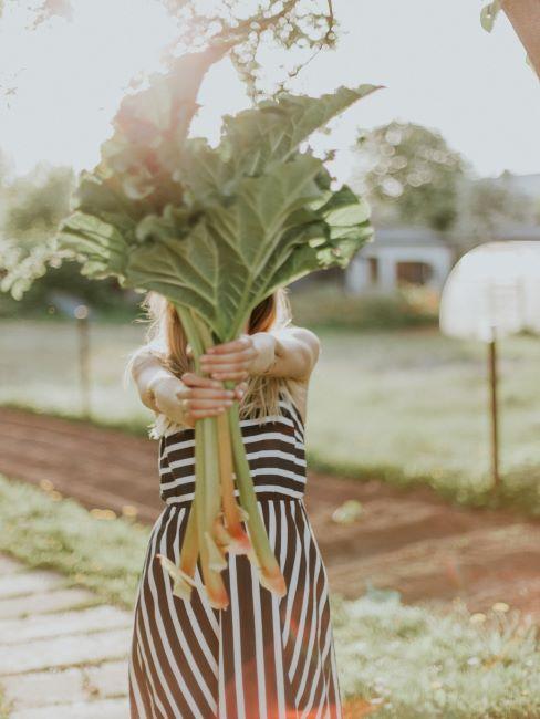 femme qui tend un bouquet de grandes feuilles vertes