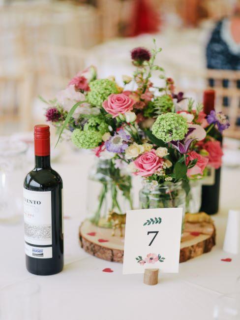 Table avec carton de table, bouteille de vin rouge et bouquet de fleurs