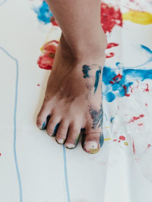 un petit pied d enfant tache de la peinture, pose sur une feuille de papier tachee de la peinture