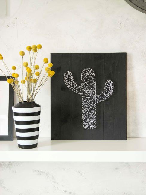 Tableau noir avec cactus sur etagere blanche avec des fleurs jaunes dans un vase raye noir et blanc