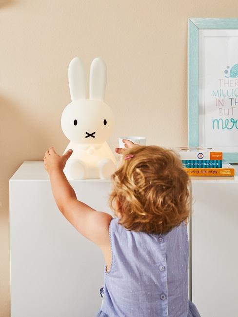 Petit enfant et veilleuse ne formede lapin sur commode blanche